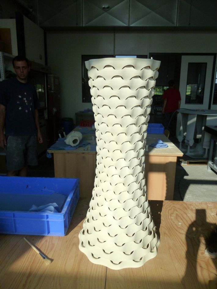 a large white vase sitting on top of a wooden table next to blue boxes and a man