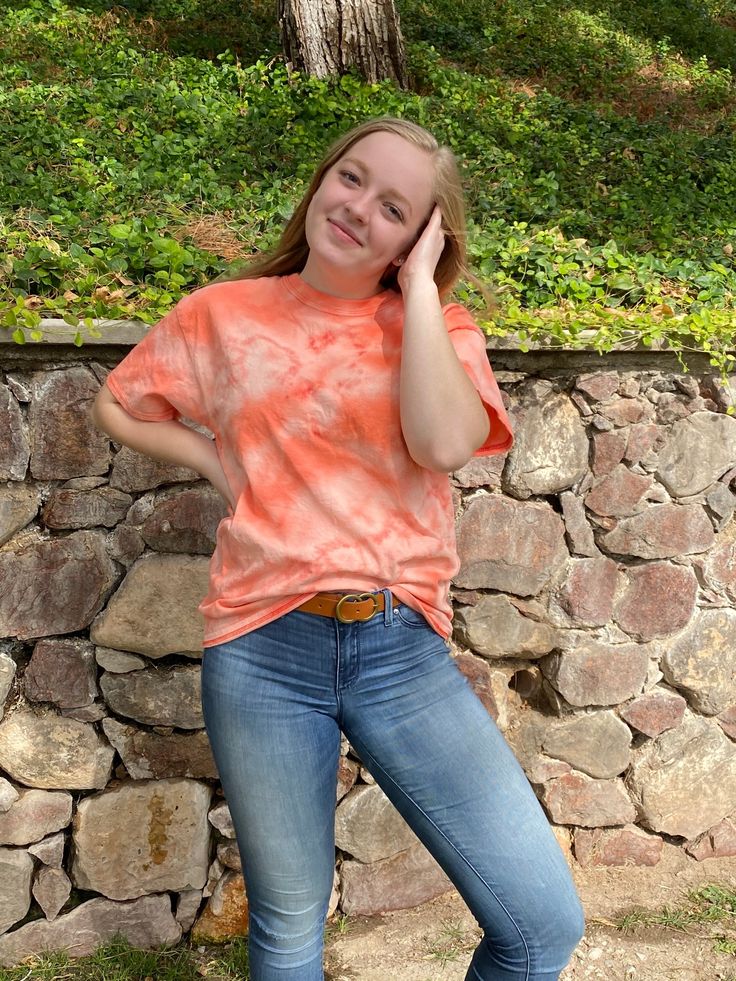 a woman leaning against a stone wall talking on her cell phone