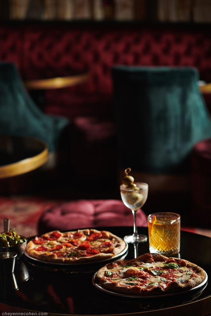 two pizzas sitting on top of a table next to a wine glass and bottle