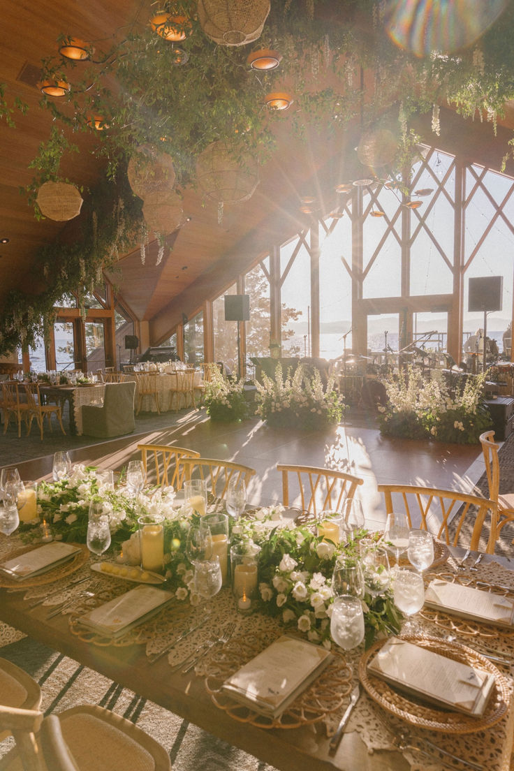 a table set up for a formal function with flowers and greenery on the tables