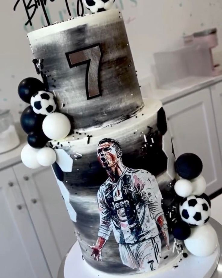 a birthday cake with an image of a soccer player on the side and balloons around it