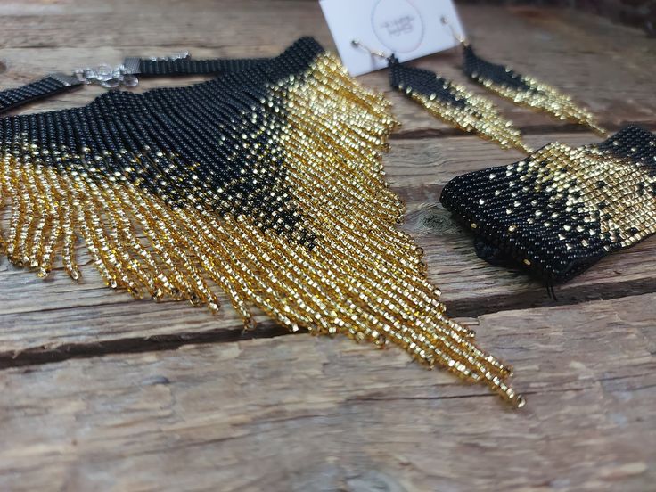 a pair of black and gold beaded purses sitting on top of a wooden table