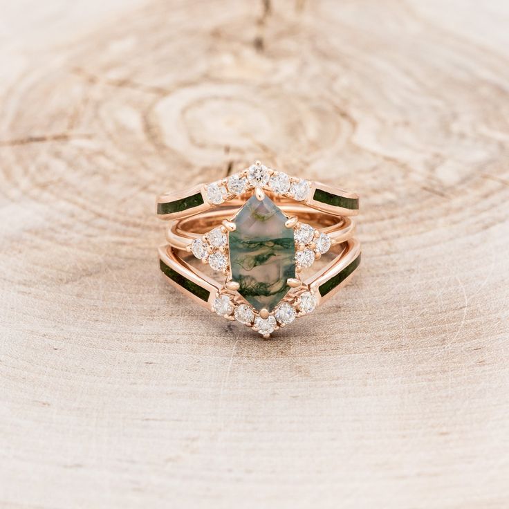 a green and white diamond ring sitting on top of a piece of wood