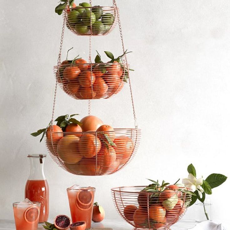 three tiered baskets filled with fruit on top of a white table next to glasses