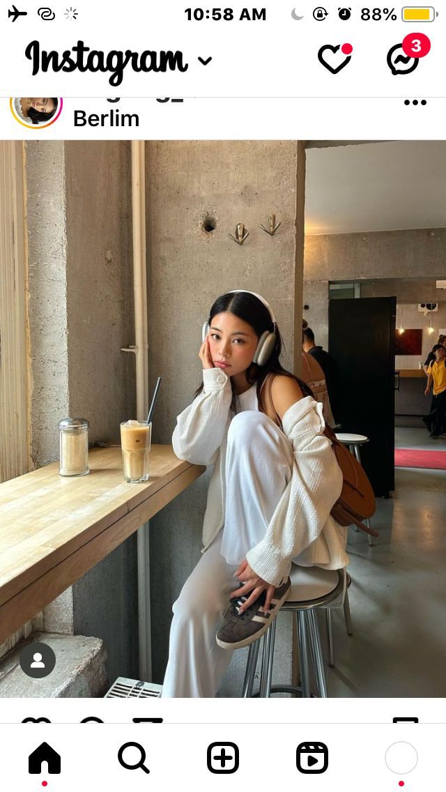 a woman sitting at a table talking on her cell phone and holding a drink in front of her face