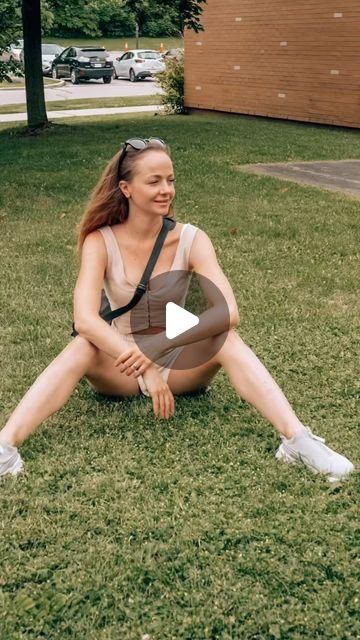 a woman sitting on the grass with her legs crossed