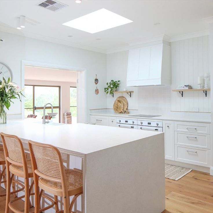 a large kitchen with white cabinets and wooden chairs in front of an island countertop