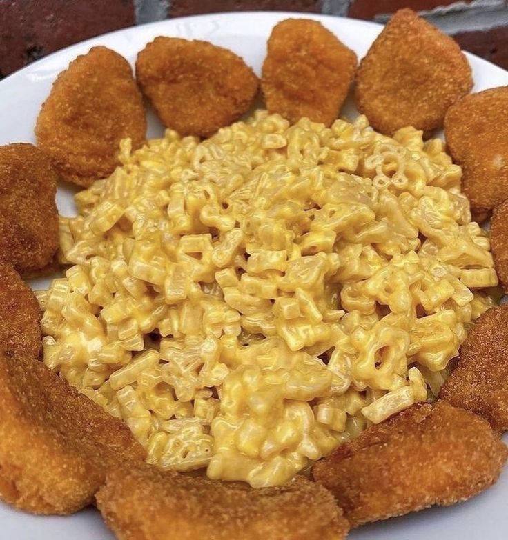 a white plate topped with macaroni and cheese next to fried chicken nuggies