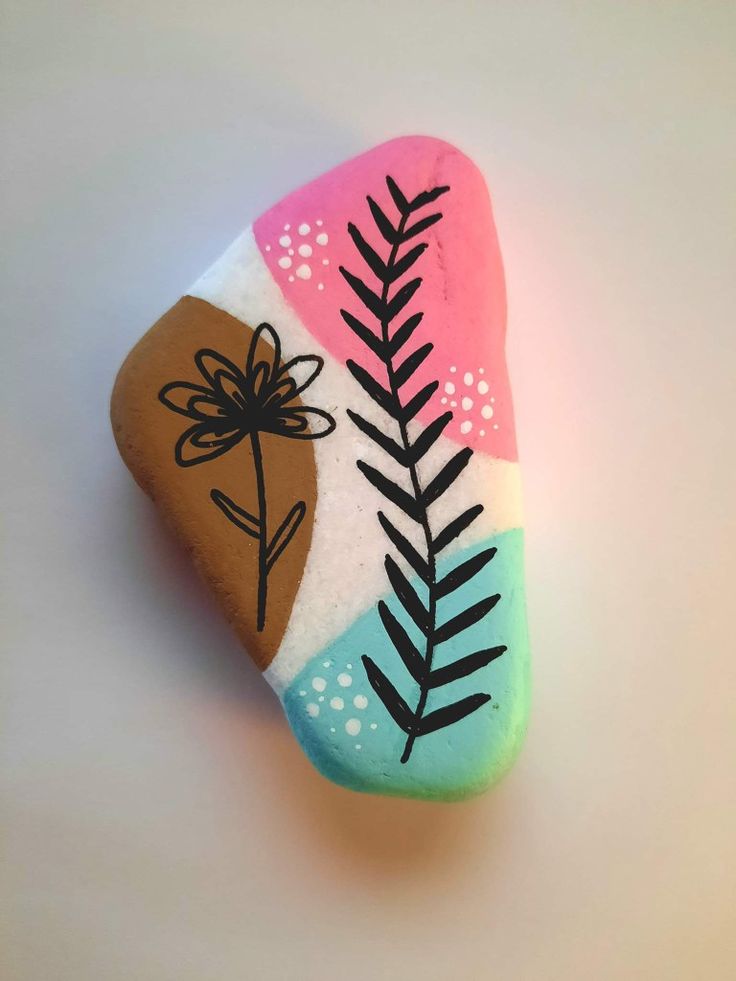 a painted rock with leaves and a flower on it