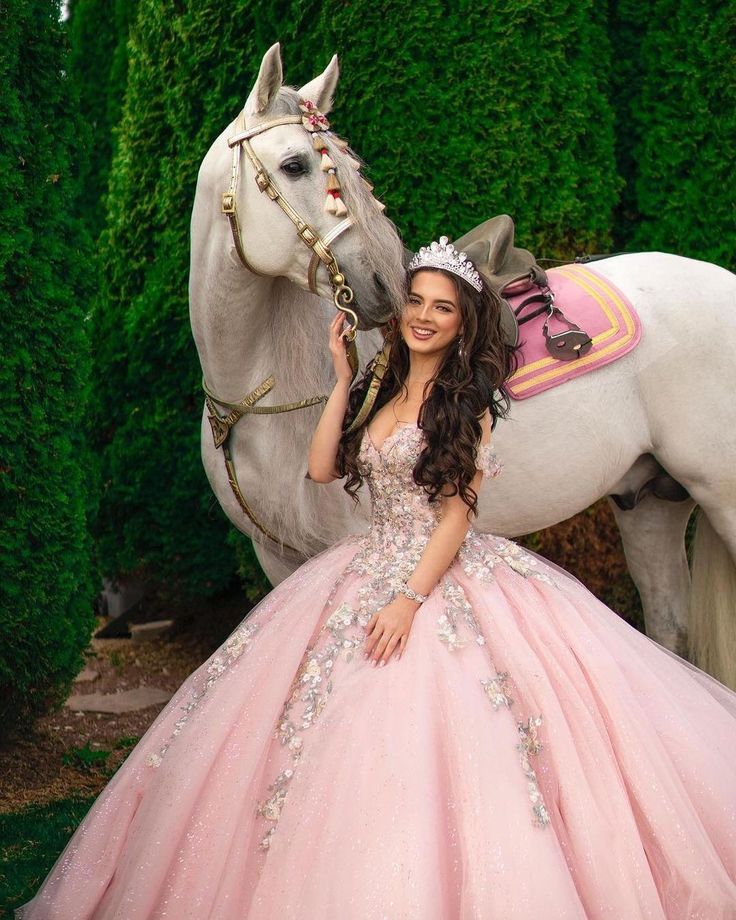 a woman in a pink dress standing next to a horse