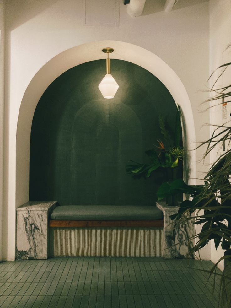 an empty room with a bench and potted plants