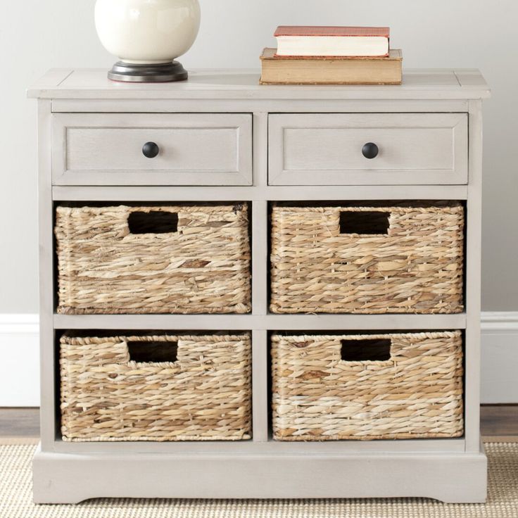 an old dresser with wicker baskets on top and a white vase next to it