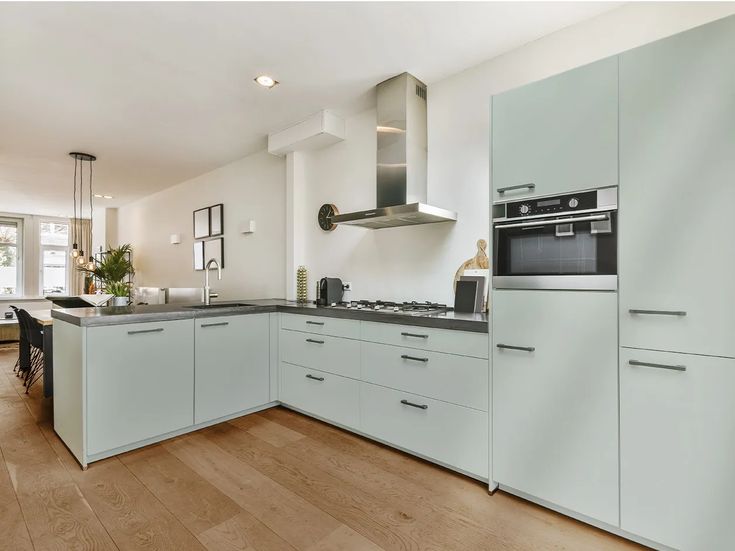 a kitchen with white cabinets and wood floors