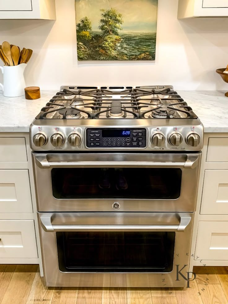 a stainless steel stove top oven in a kitchen with white cabinets and wood flooring