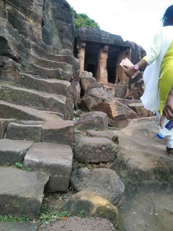 a woman walking up some steps in the middle of an ancient city with large rocks