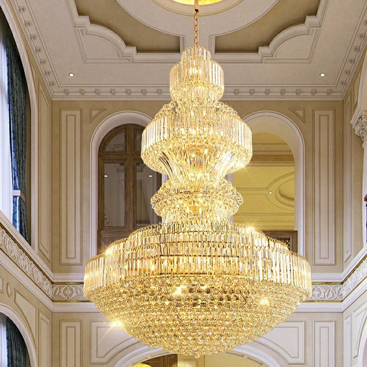 a large chandelier hanging from the ceiling in a room with columns and windows