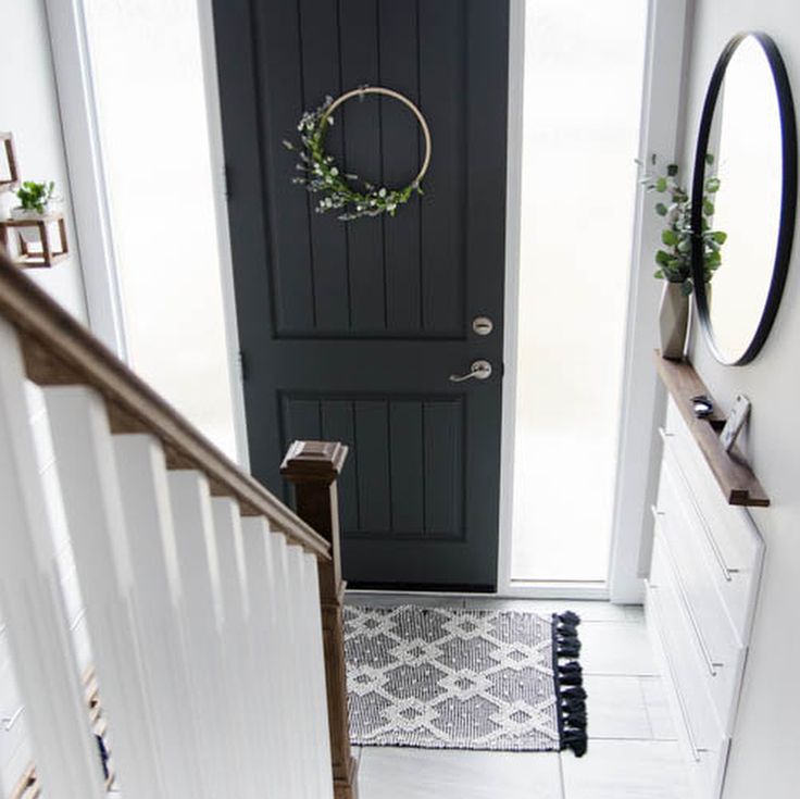 a black door with a wreath hanging on it's side next to a white stair case