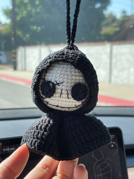 someone is holding up a crocheted doll in their hand while they are driving