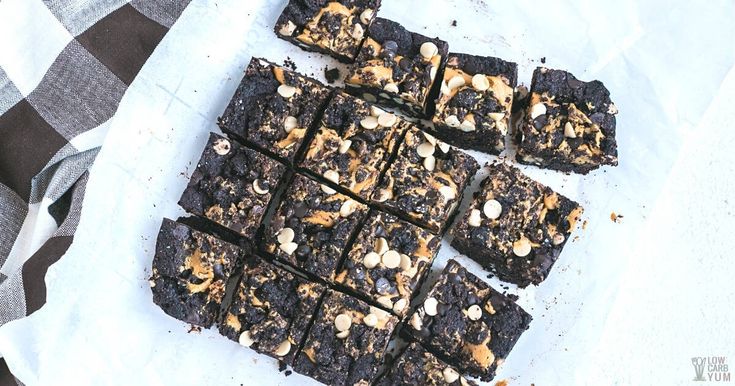 chocolate brownies cut into squares on top of a checkered table cloth with nuts