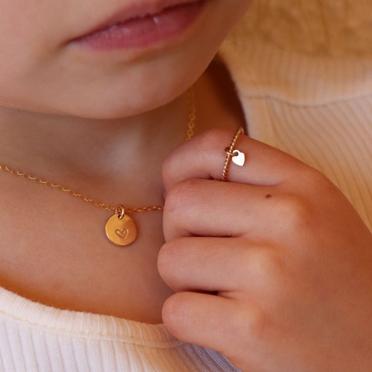 Add some love to your little one's wardrobe with our Tiny Heart Charmed Ring. This children's ring is a favorite in our Tiny Token children's collection and features a delicate 14k gold filled or sterling silver spiral band with a cute heart charm. Perfect for tiny fingers and big smiles. Make their day with this adorable keepsake ring! Our Tiny Token Collection is perfect for children ages 10 and under. Shop our Heart Charmed Ring for a ring sizes 4 and up. Not sure what size to get your little Cute Huggie Jewelry For Valentine's Day, Dainty Adjustable Tiny Heart Ring, Cute Gold Birthstone Jewelry, Cute Gold Heart Ring As A Gift, Cute Gold Heart Ring As Gift, Cute Gold Heart Ring For Gift, Cute Adjustable Heart Pendant Jewelry, Cute Gold Stackable Jewelry, Dainty Hypoallergenic Heart Ring