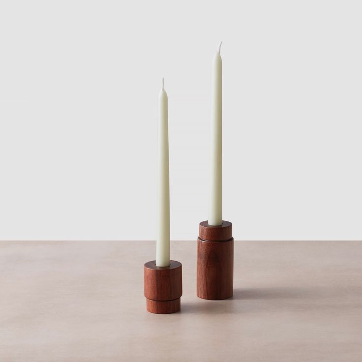 two tall candles sitting in front of each other