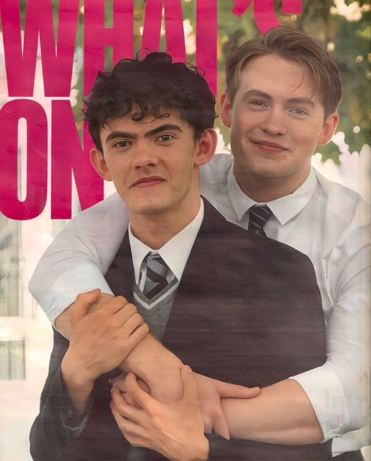 two young men are hugging each other in front of a sign that says what's on?