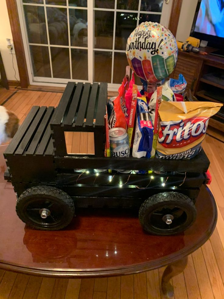 a toy truck with balloons and candy on it sitting on top of a table in front of a window