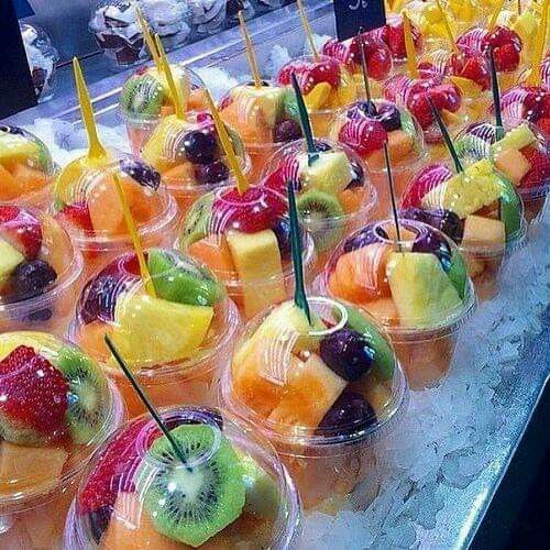 many different kinds of fruit in plastic cups