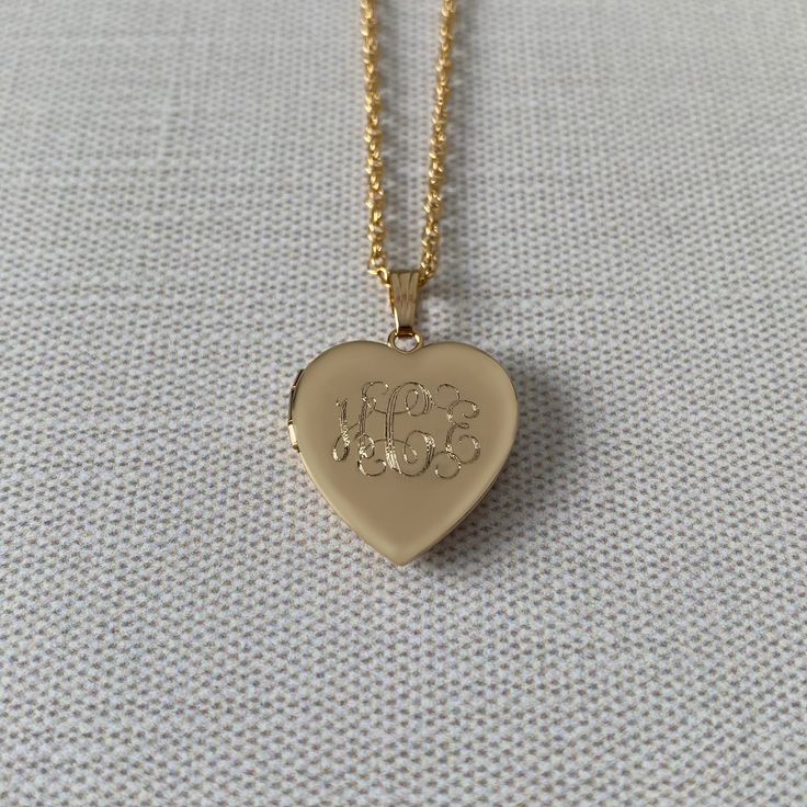 An adult-size plain polished 14K yellow gold-filled heart-shaped locket on a rope chain necklace. The outer shell is solid gold pressure-bonded to an inner core of high-quality brass. Locket Dimensions: 19 mm W x 18 mm H Chain Length: 18" Gold Heart Pendant Jewelry With Engraving Option, Gold Heart Pendant Necklace With Initials, Heart Shaped Locket Necklace With Polished Finish As Gift, Gold Heart Necklace With Initials, Classic Gold Locket Necklace With Heart Charm, Engraved Heart Shaped 14k Gold Locket Necklace, Engraved 14k Gold Heart Locket Necklace, Gold Double Heart Necklace For Memorial, Classic Personalized Heart Locket Necklace