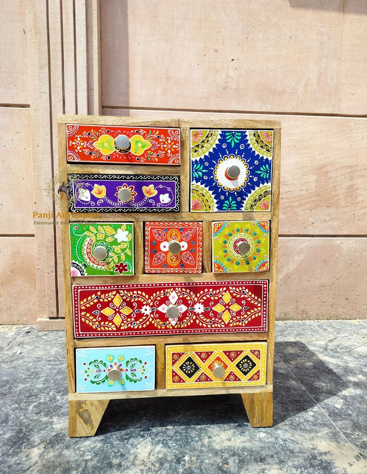 a multicolored wooden cabinet with many different designs on the front and side panels