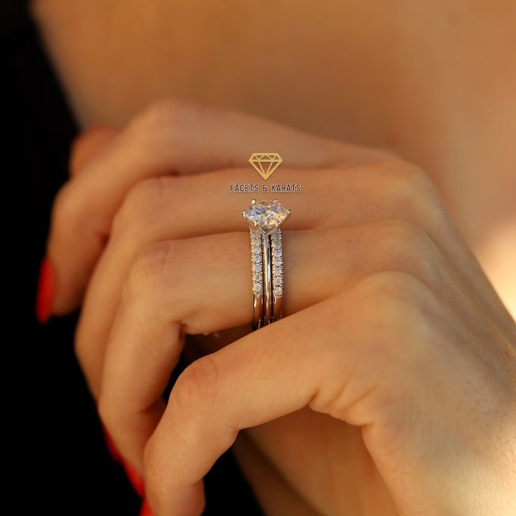 a woman's hand holding a diamond ring with two diamonds on it and the other hand