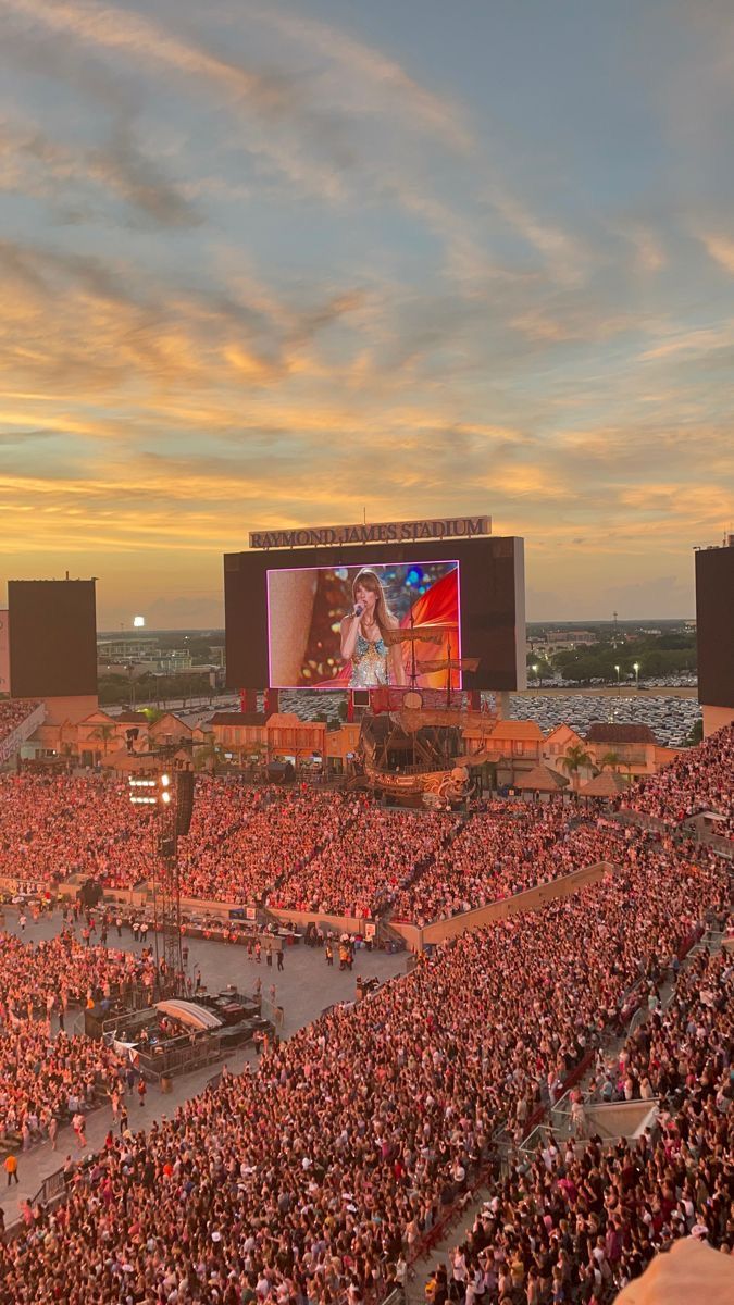 a large crowd is watching a concert on the big screen in front of an audience