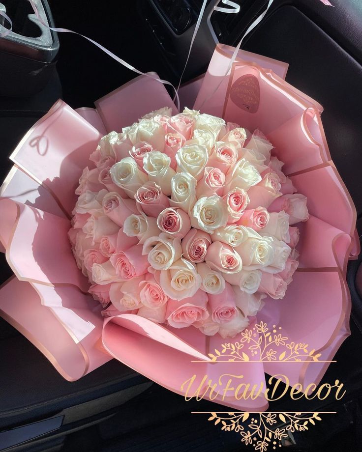 a pink and white bouquet sitting on top of a car dashboard