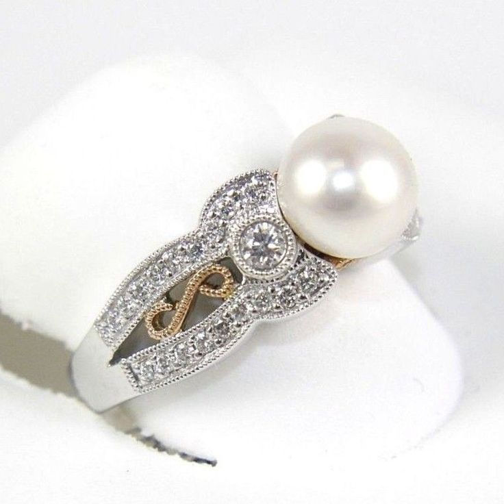 a pearl and diamond ring on a white surface