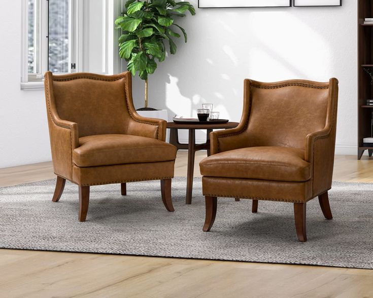 two brown chairs sitting next to each other on top of a rug