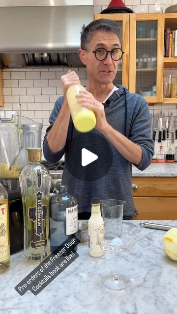 a man standing in front of a counter with bottles and glasses on top of it