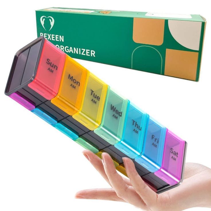 a hand holding a multicolored pill organizer