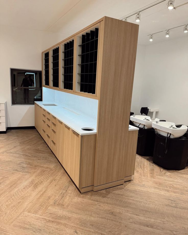 an empty room with wooden cabinets and white counter tops in the center, along with black chairs