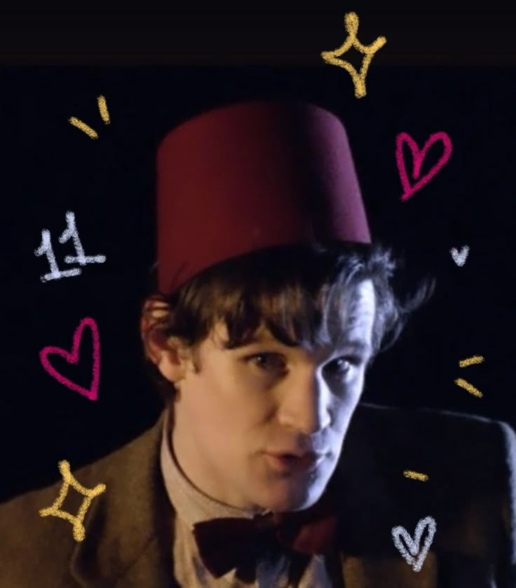 a man wearing a red hat and bow tie with hearts drawn on the wall behind him