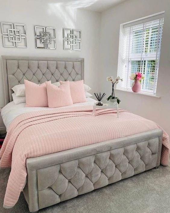 a bed with pink sheets and pillows in a bedroom