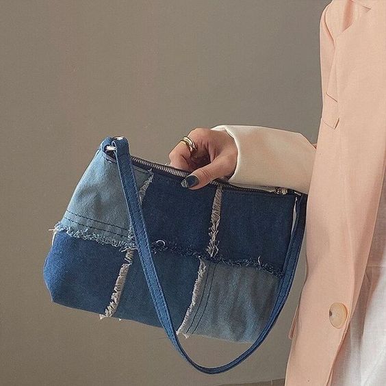 a woman holding a denim purse with holes in the front and side pockets on both sides