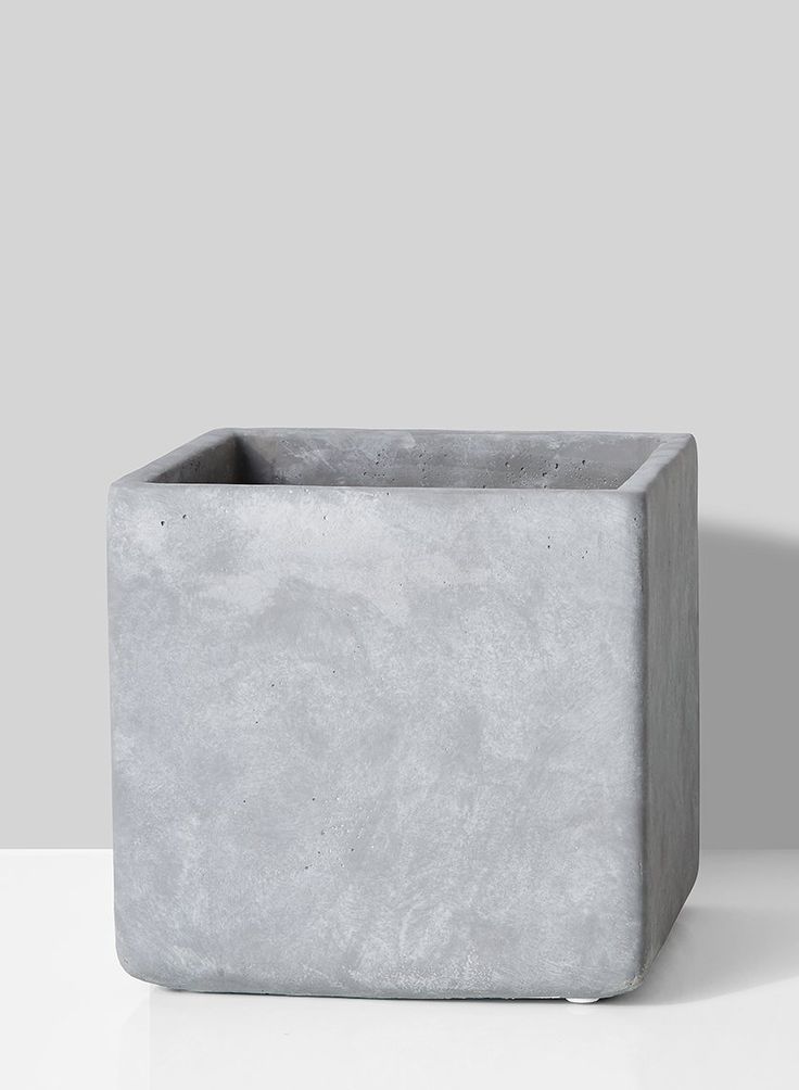 a square concrete planter sitting on top of a white table next to a gray wall