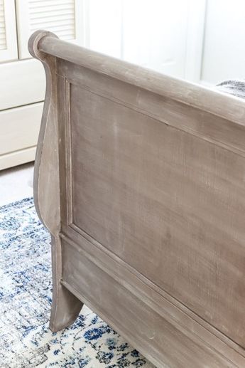 a close up of a bed with a blue and white rug on the floor next to it