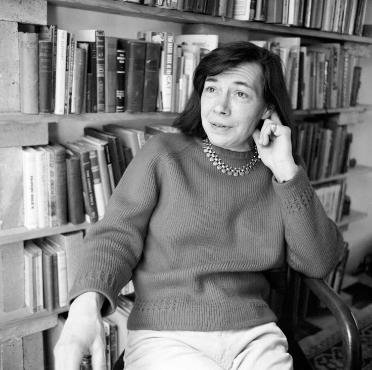 a woman sitting in a chair talking on her cell phone next to bookshelves