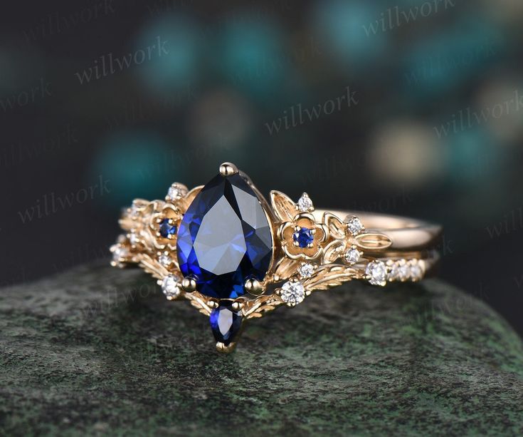 a blue and white diamond ring sitting on top of a rock