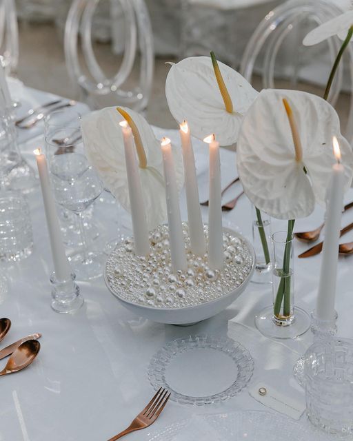 the table is set with white flowers and candles