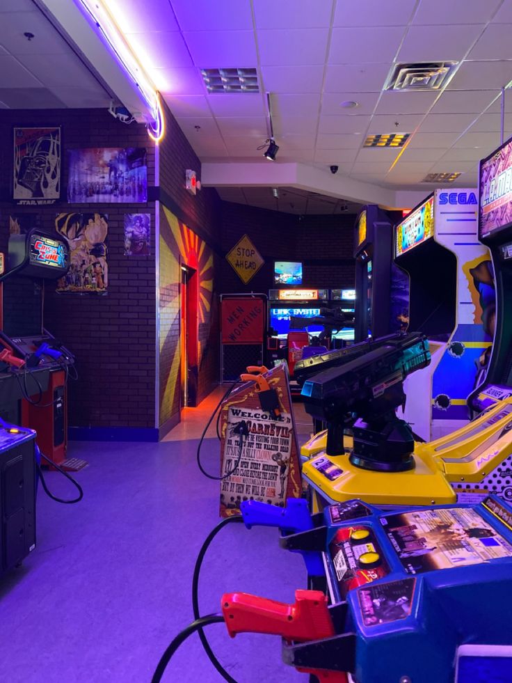 a room filled with video game machines and arcade gaming equipment on the walls, in front of purple lighting