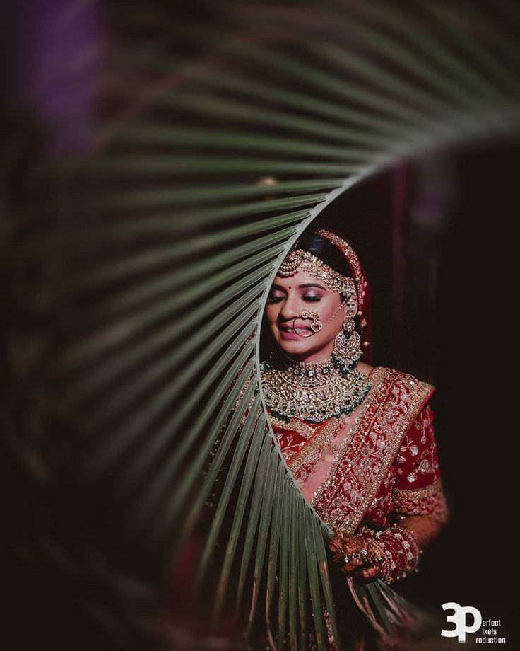 a woman in a red and gold bridal outfit looking at the camera with her eyes closed