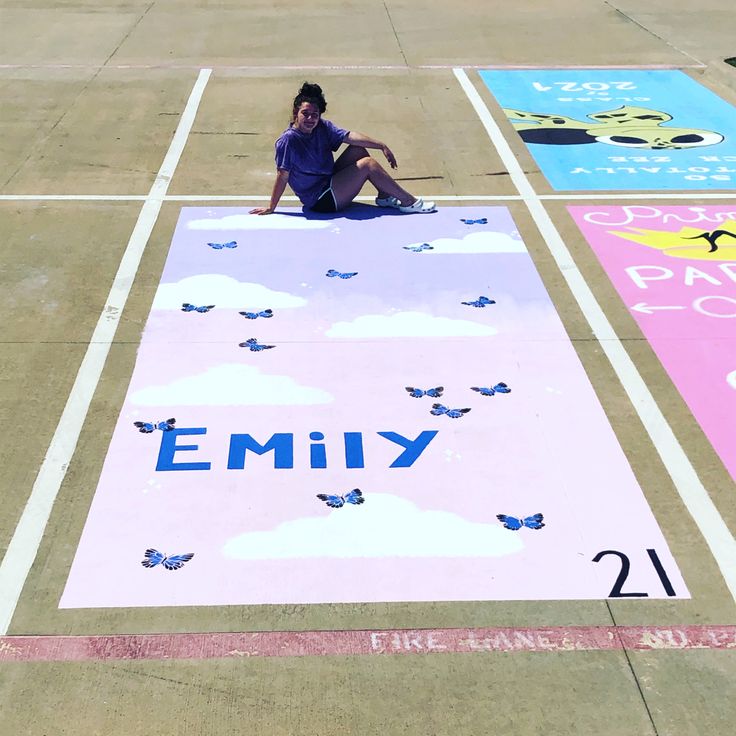 a woman sitting on the ground in front of a painted area