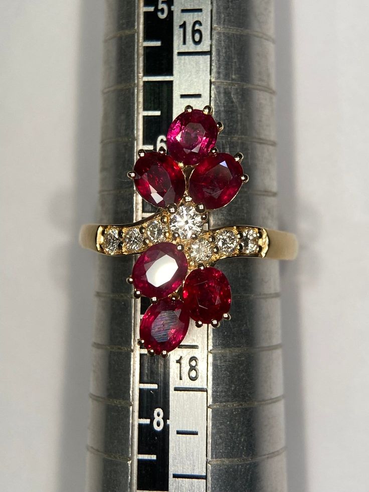 a close up of a ring on top of a measuring ruler with red and white stones